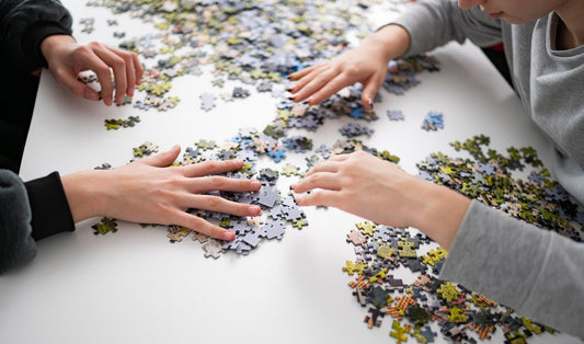 Varias personas montando juntas un puzzle sobre una mesa