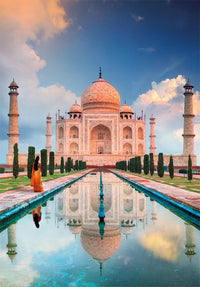 Ilustración del puzzle Taj Mahal 1500 piezas Clementoni, con el mausoleo de mármol y sus minaretes reflejados en el estanque y una mujer con sari naranja al atardecer