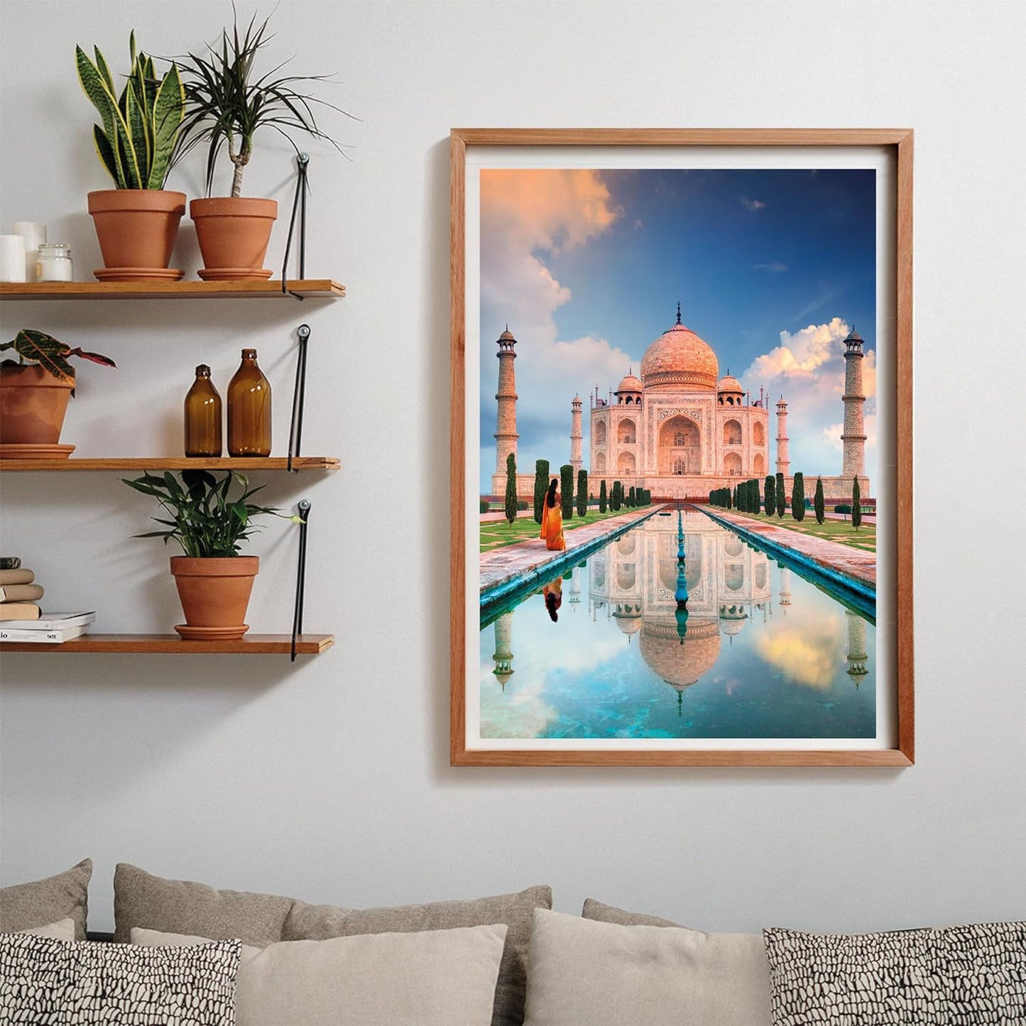Puzzle Taj Mahal 1500 piezas Clementoni montado y enmarcado en madera clara sobre pared, junto a estanterías con plantas y sofá con cojines