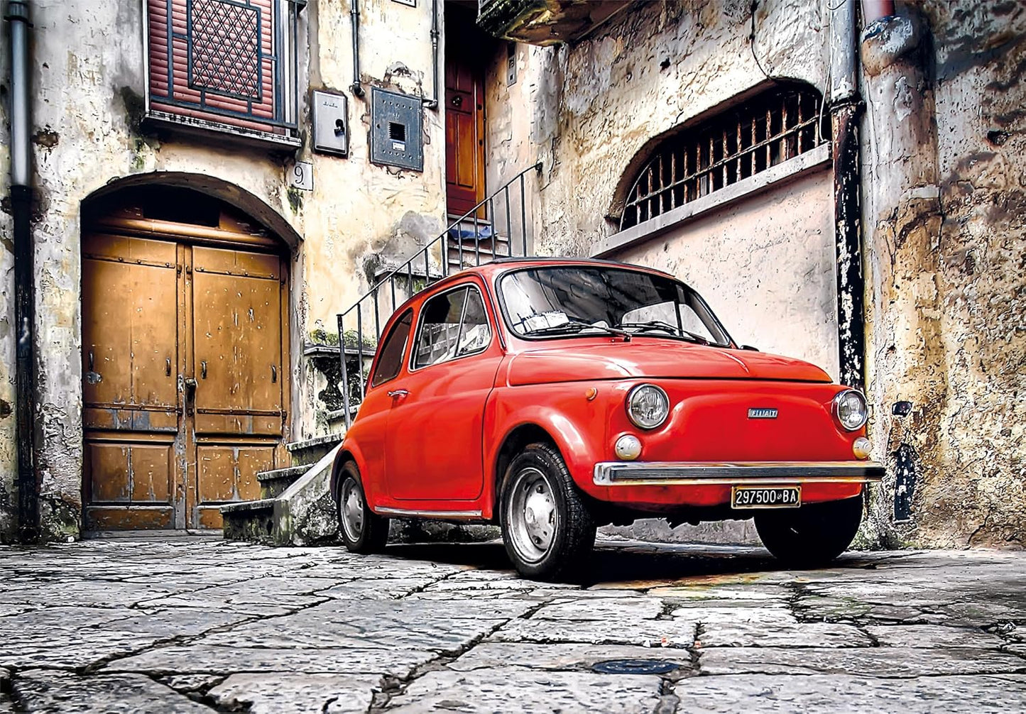 Ilustración del puzzle Coche Fiat Rojo de 500 piezas de Clementoni: un Fiat 500 rojo aparcado en una calle empedrada de un casco antiguo italiano