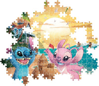 Montaje parcial del Puzzle Disney Stitch 500 piezas Clementoni, con piezas encajadas mostrando a Stitch y Angel en la playa junto al castillo de arena y piezas sueltas alrededor.