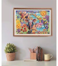 Puzzle Carnaval de Elefantes 500 piezas Clementoni montado y enmarcado en madera sobre una pared, con la escena de elefantes ornamentados entre flores y un sol con rostro; debajo, una planta, un bote de lápices, libros y una taza.