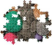 Montaje parcial del Puzzle Gatito Esponjoso 500 piezas Clementoni, con piezas encajadas mostrando al gatito gris entre ovillos de lana de colores y piezas sueltas alrededor.