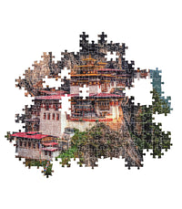 Montaje parcial del Puzzle El Nido del Tigre 500 piezas Clementoni, con piezas encajadas mostrando el monasterio de Paro Taktsang en el acantilado y piezas sueltas alrededor.