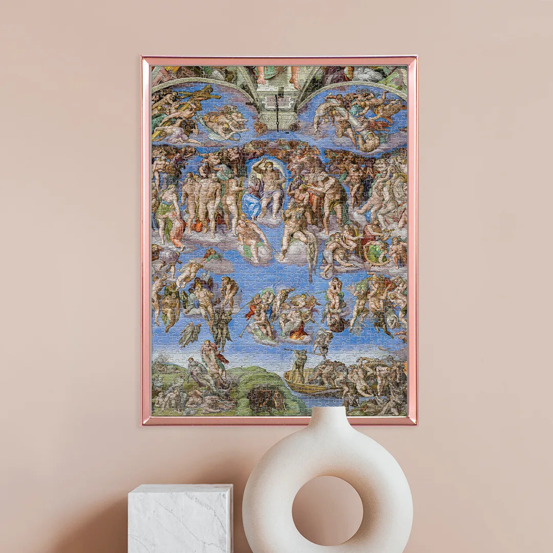 Puzzle El Juicio Universal Michelangelo 1000 piezas Clementoni Museum Collection montado y enmarcado en cobre sobre pared rosa, junto a un jarrón blanco decorativo