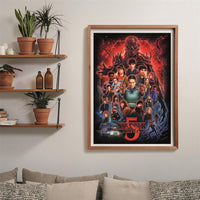 Puzzle Stranger Things Temporada 5 1000 piezas Clementoni montado y enmarcado en madera sobre una pared, con el collage de personajes de la serie; al lado, estantes con plantas y libros, y debajo un sofá con cojines.