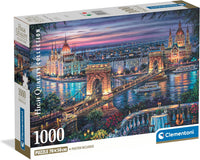 Caja del Puzzle Paisaje Nocturno de Budapest 1000 piezas Clementoni. Pintura del Puente de las Cadenas sobre el Danubio al anochecer, con el Parlamento iluminado y una mesa con guitarra en primer plano.
