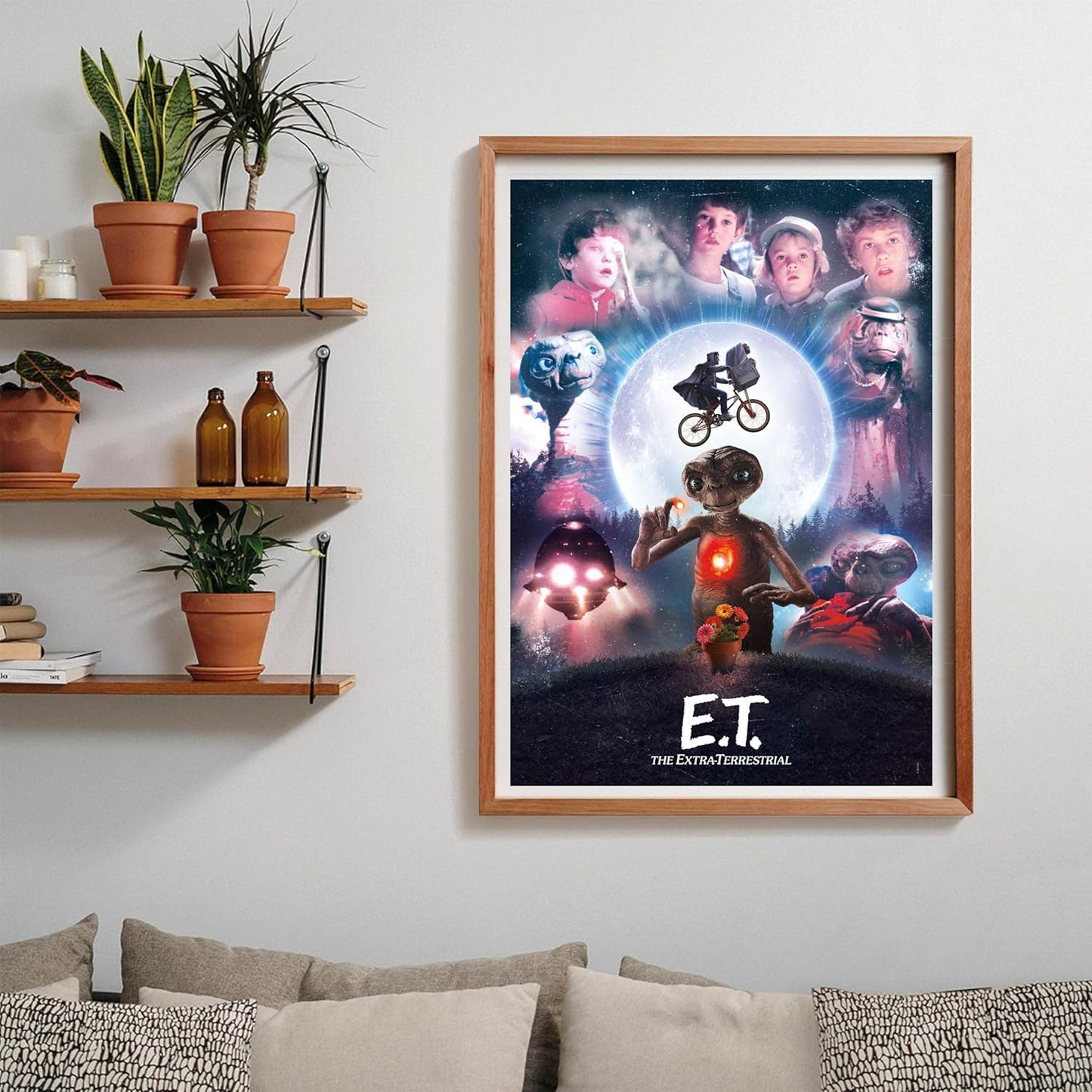 Puzzle E.T. El Extraterrestre 1000 piezas Clementoni montado y enmarcado en madera sobre una pared, con el collage de la película; al lado, estantes con plantas y libros, y debajo un sofá con cojines.