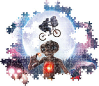 Montaje parcial del Puzzle E.T. El Extraterrestre 1000 piezas Clementoni, con piezas encajadas mostrando a E.T. y la escena de la bicicleta ante la luna, y piezas sueltas alrededor.