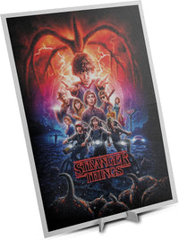 Póster incluido del Puzzle Stranger Things Temporada 2 1000 piezas Clementoni, con Eleven y el Azotamentes al fondo, los personajes en bicicleta y el logo en rojo.