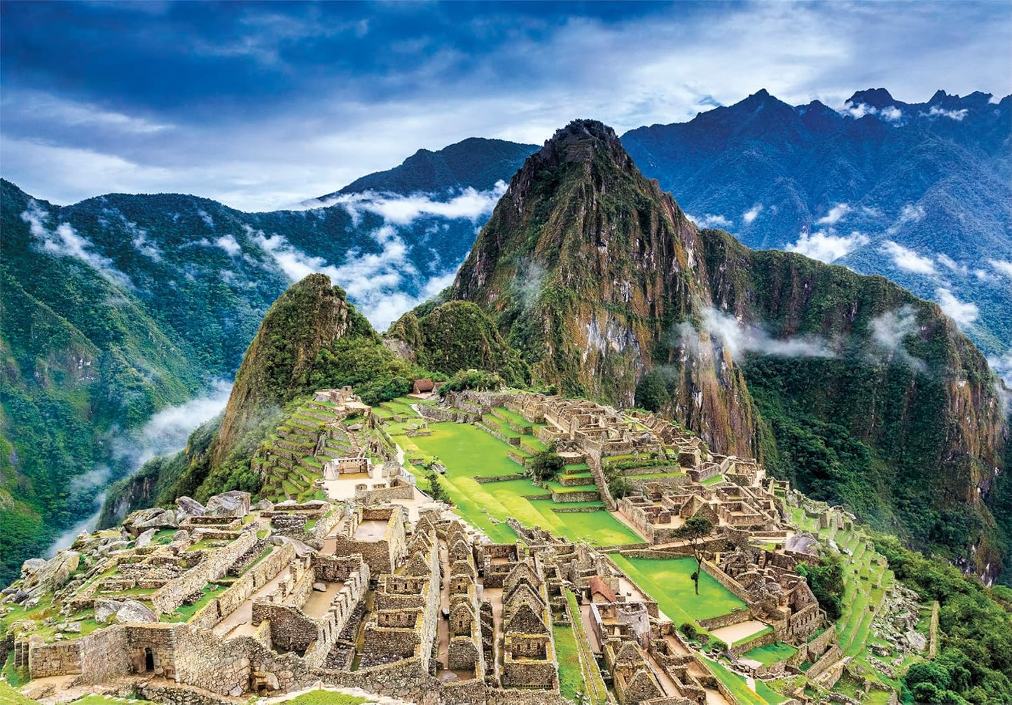 Ilustración del Puzzle Machu Picchu 1000 piezas Clementoni. Vista aérea de la ciudadela inca de Machu Picchu con el Huayna Picchu al fondo, entre montañas verdes y nubes.