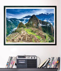 Puzzle Machu Picchu 1000 piezas Clementoni montado y enmarcado en negro sobre una pared, con la vista aérea de la ciudadela inca; debajo, un radiocasete y cintas VHS en una estantería.