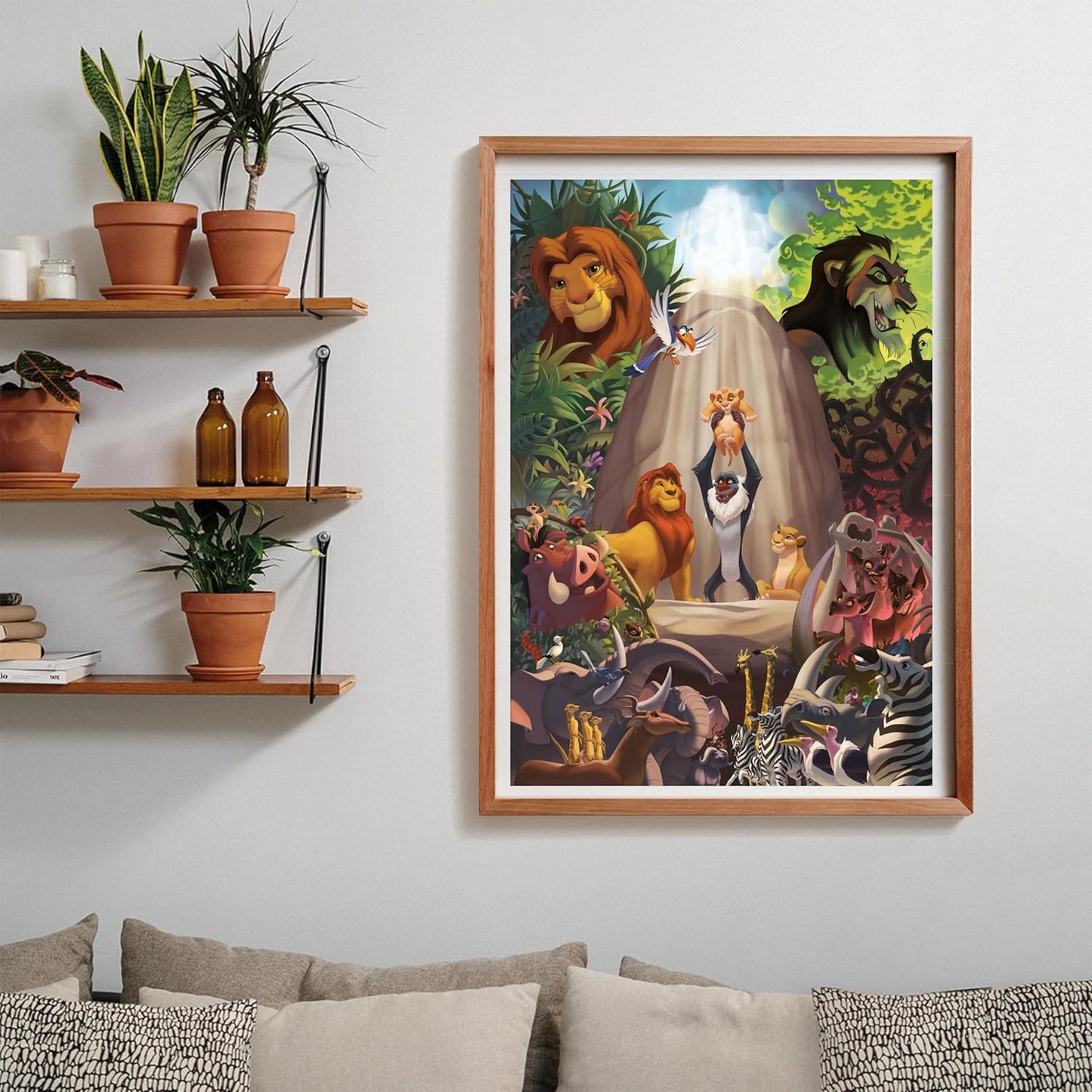 Puzzle El Rey León 1000 piezas Clementoni montado y enmarcado en madera sobre una pared, con la escena de Rafiki presentando a Simba; al lado, estantes con plantas y libros, y debajo un sofá con cojines.