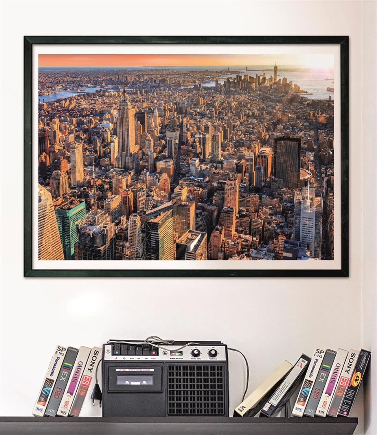 Puzzle Nueva York 1000 piezas Clementoni montado y enmarcado en negro sobre pared, sobre un estante con cintas VHS y radio-casete vintage
