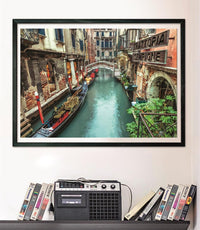 Puzzle Canal de Venecia 1000 piezas Clementoni montado y enmarcado en negro sobre pared, sobre un estante con cintas VHS y radio-casete vintage