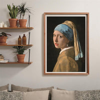 Puzzle La Joven de la Perla 1000 piezas Clementoni montado y enmarcado en madera clara sobre pared, junto a estanterías con plantas y sofá con cojines