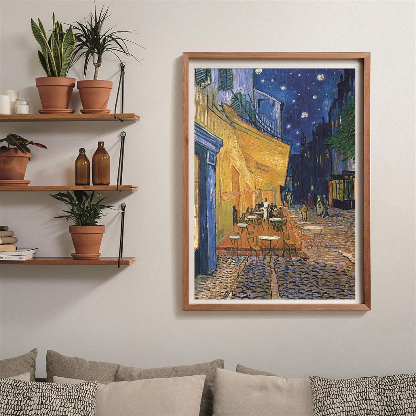 Puzzle Terraza de Café por la Noche Van Gogh 1000 piezas Clementoni montado y enmarcado en madera clara sobre pared, junto a estanterías con plantas y sofá con cojines